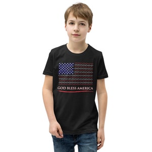 Op de afbeelding: Zwart T-shirt met een gestileerd ontwerp van de Amerikaanse vlag. De vlag bevat witte en rode elementen, met een veld van blauwe sterren. De tekst "GOD BLESS AMERICA" staat eronder in het wit.