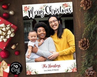 May include: A Christmas photo booth prop with a white background and red and green floral accents. The text "Merry Christmas" is written in black cursive font. The prop also includes the text "The Hensleys, Leo, Haley & Skylar" in red cursive font.