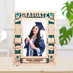 May include: A wooden photo frame with a graduation theme. The frame has a cutout design with a graduation cap, gown, diploma, and books. The frame is personalized with the name "Emma Johnson" and the text "North View High 2023".