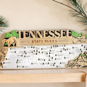 Peut inclure: Carte en bois des parcs d'État du Tennessee avec des détails découpés au laser. La carte présente un contour détaillé de l'État, avec de petites icônes d'arbres marquant les emplacements des parcs. Le haut de la carte indique "Tennessee State Parks".