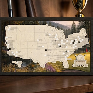 Può includere: Mappa in legno del tracciatore di campi da golf degli Stati Uniti, con una cornice scura. La mappa è di colore chiaro con piccoli indicatori bianchi e spilli neri. L'angolo in basso a destra presenta una grafica di palla da golf e mazza con il testo "TOP COURSE TRACKER" e "ATHLETE NAME".