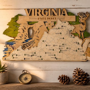 May include: A layered wooden wall art piece depicting a map of Virginia State Parks. The design features a natural wood finish with green accents, a deer silhouette, a fish, and a rock arch. The text VIRGINIA STATE PARKS is engraved at the top.
