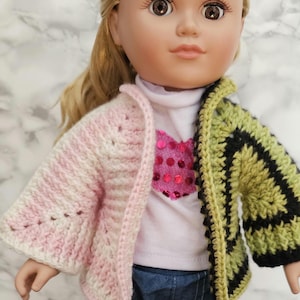 May include: A doll wearing a pink and white crocheted cardigan, a white shirt with a pink heart, and blue jeans.