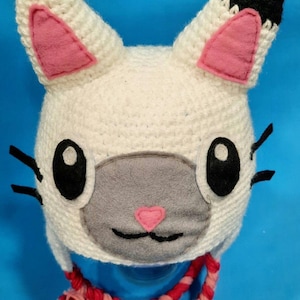 May include: White crocheted cat hat with pink ears and a gray felt face. The hat has a red and pink braided cord.