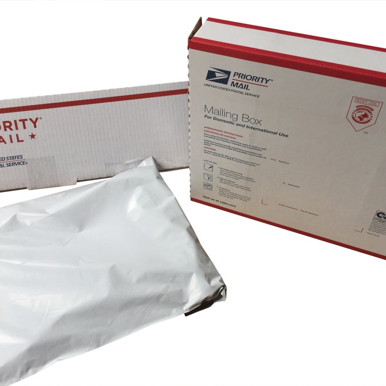 May include: A white Priority Mail mailing box with red and blue accents. The box is labeled "Mailing Box" and "For Domestic and International Use". The box is sitting on a white surface next to a white plastic poly mailer.