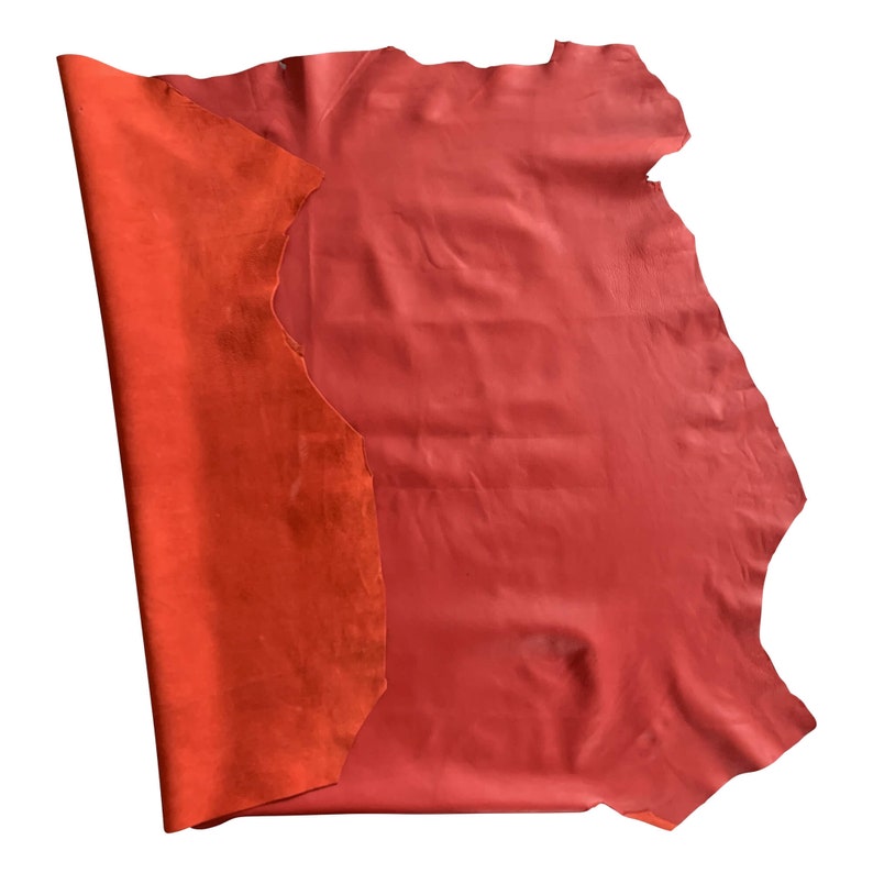 May include: A piece of red leather with a suede-like texture on one side. The leather is folded in half, revealing both sides.
