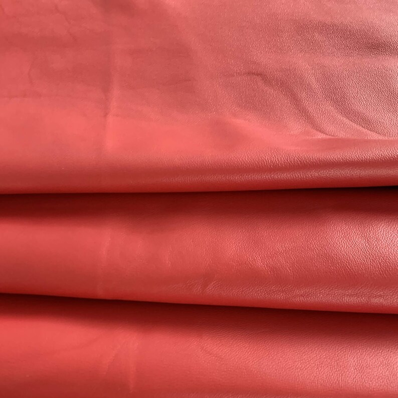May include: Close-up of a folded piece of red leather. The leather has a smooth, slightly textured surface.