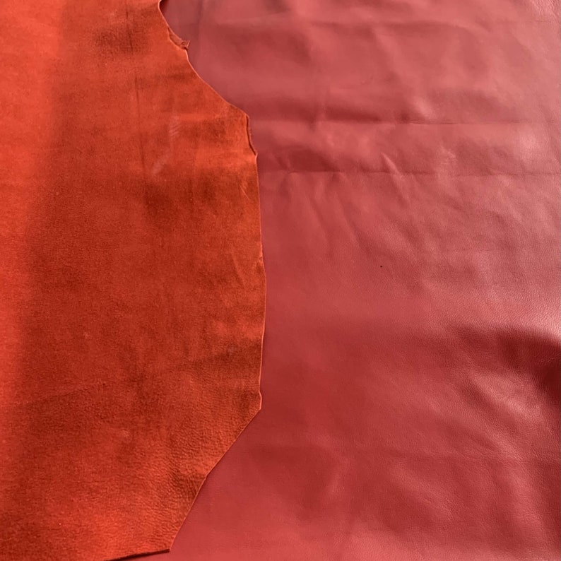 May include: Two pieces of red leather, one smooth and one suede. The smooth leather is on the right and the suede is on the left.
