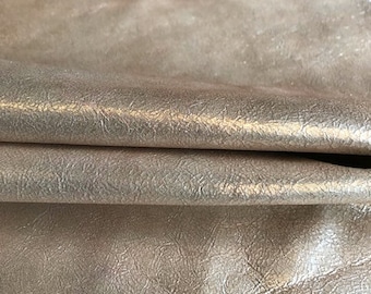May include: Close-up of a metallic silver leather fabric with a textured surface.