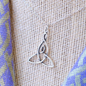 May include: A silver Celtic knot pendant necklace. The pendant is a traditional knot design with a delicate, intricate pattern. The necklace is on a silver chain.