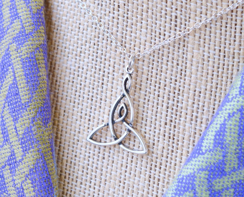 May include: A silver Celtic knot pendant necklace. The pendant is a traditional knot design with a delicate, intricate pattern. The necklace is on a silver chain.