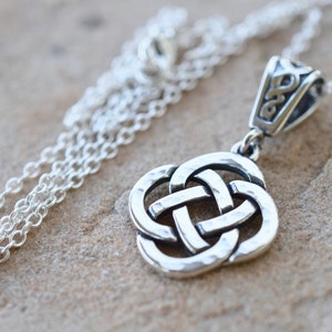 May include: Silver Celtic knot pendant necklace with a hammered finish. The pendant is attached to a silver chain.