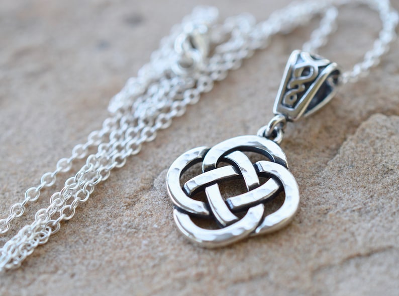 May include: Silver Celtic knot pendant necklace with a hammered finish. The pendant is attached to a silver chain.