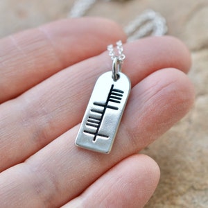 May include: Silver necklace with a rectangular pendant featuring a Celtic knot design.