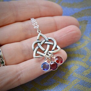 Puede incluir: Collar de plata con colgante de nudo celta y tres colgantes de cristal. Los colgantes son rojos, azules y rojos.