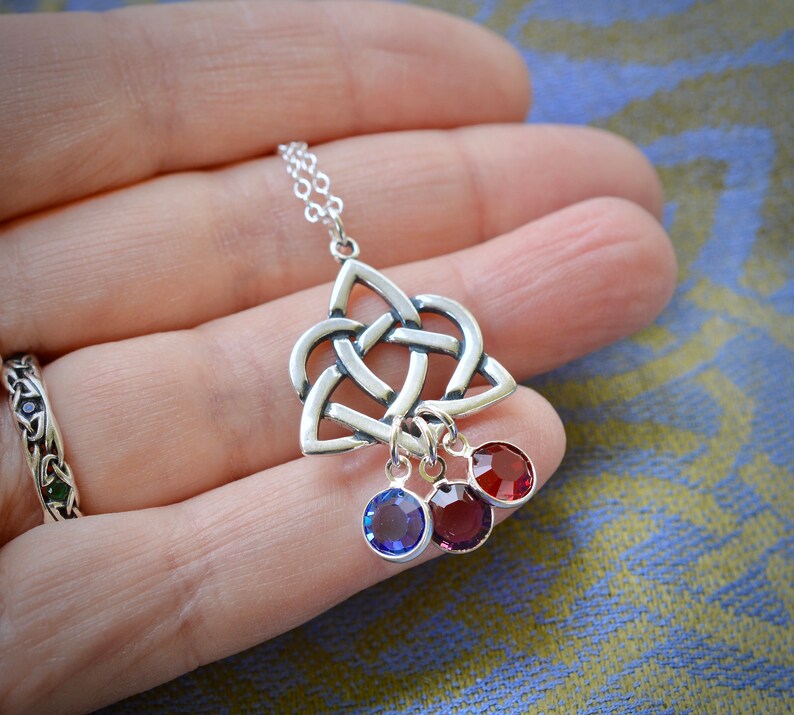 Puede incluir: Collar de plata con colgante de nudo celta y tres colgantes de cristal. Los colgantes son rojos, azules y rojos.