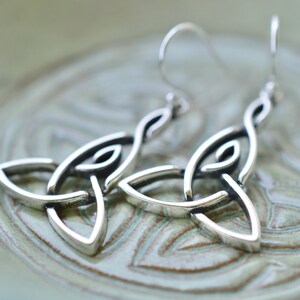 May include: Silver Celtic knot earrings with a simple, elegant design. The earrings are made of sterling silver and have a polished finish.