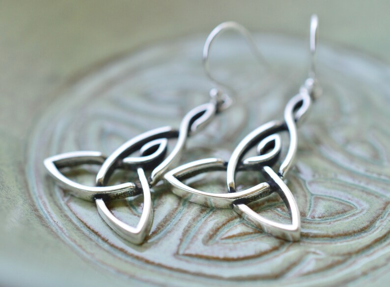 May include: Silver Celtic knot earrings with a simple, elegant design. The earrings are made of sterling silver and have a polished finish.