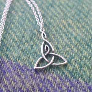 May include: A silver Celtic knot pendant necklace with a delicate chain. The pendant is a traditional triquetra design, symbolizing the trinity.