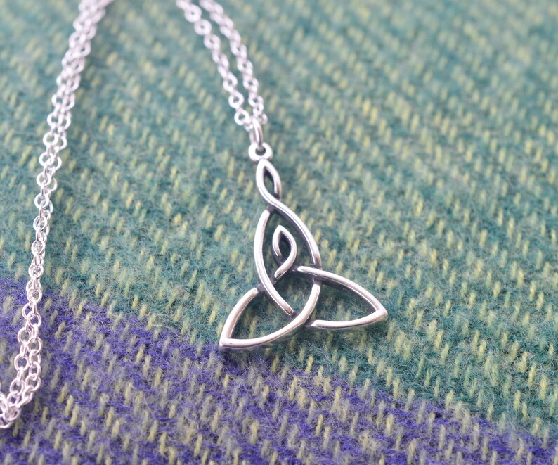 May include: A silver Celtic knot pendant necklace with a delicate chain. The pendant is a traditional triquetra design, symbolizing the trinity.