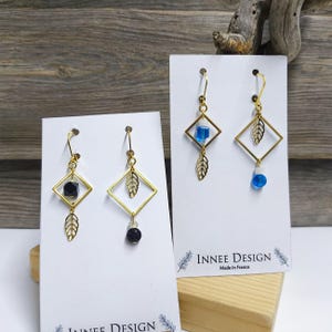 Asymmetrische ruitvormige bladoorbellen van zwart of blauw glas en verguld roestvrij staal.