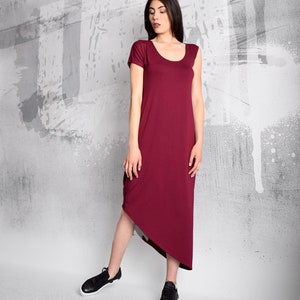 May include: A burgundy midi dress with a scoop neck and short sleeves. The dress has a high-low hemline, with the front hemline ending above the knee and the back hemline ending below the knee.