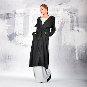 May include: A long black hooded cardigan with a tie belt. The cardigan is made of a soft, comfortable fabric and has a relaxed fit.