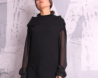 May include: A black layered tunic with long sleeves and a high neckline. The tunic is worn with black leggings and black ankle boots.