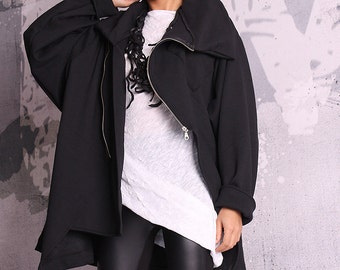 May include: A black oversized jacket with a zipper closure and a high collar. The jacket is worn over a white long-sleeved shirt and black leggings.