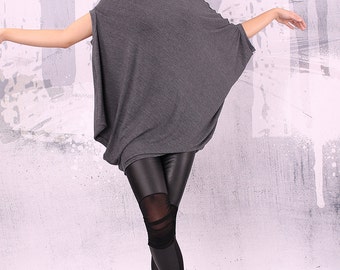 May include: A gray oversized tunic top with a relaxed fit and long sleeves. The model is wearing black leggings with mesh panels and black fur-trimmed boots.