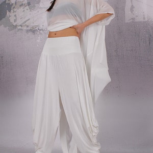 May include: White wide-leg pants with a loose, flowing fit. The pants have a high waist and a gathered detail at the ankles.