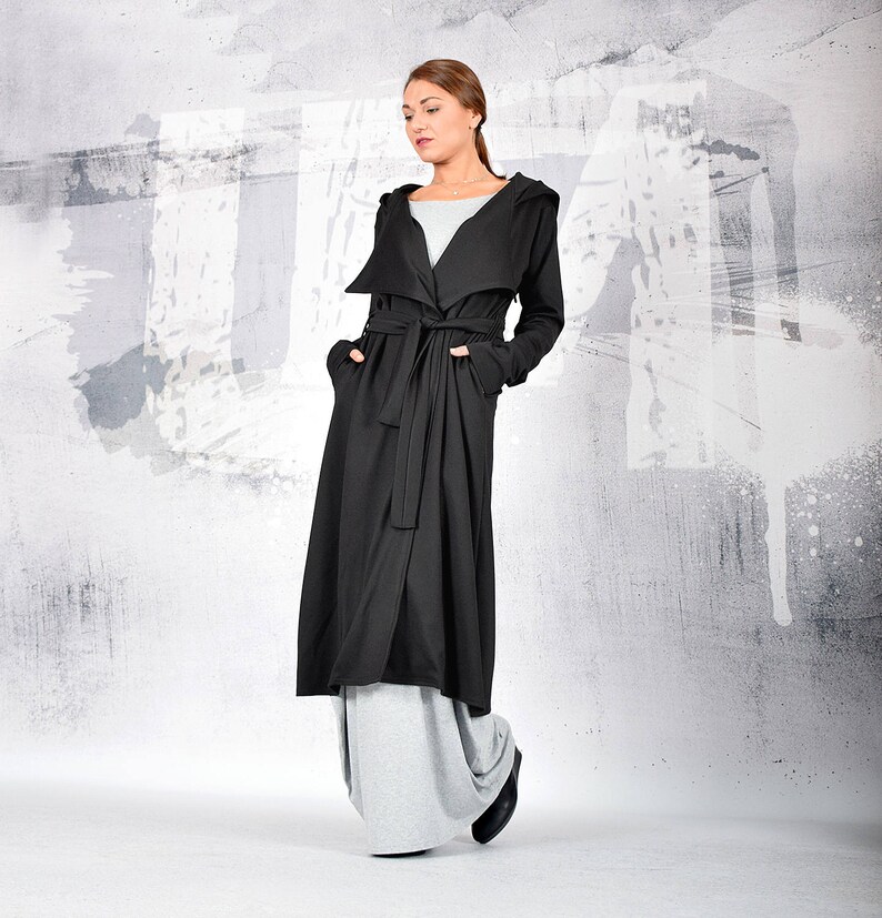 May include: A long black hooded cardigan with a tie belt. The cardigan is made of a soft, comfortable fabric and has a relaxed fit.