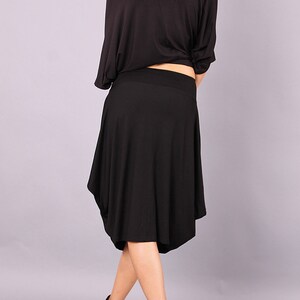 May include: A black off-the-shoulder top with a loose fit and a black skirt with a flowing, asymmetrical hem.