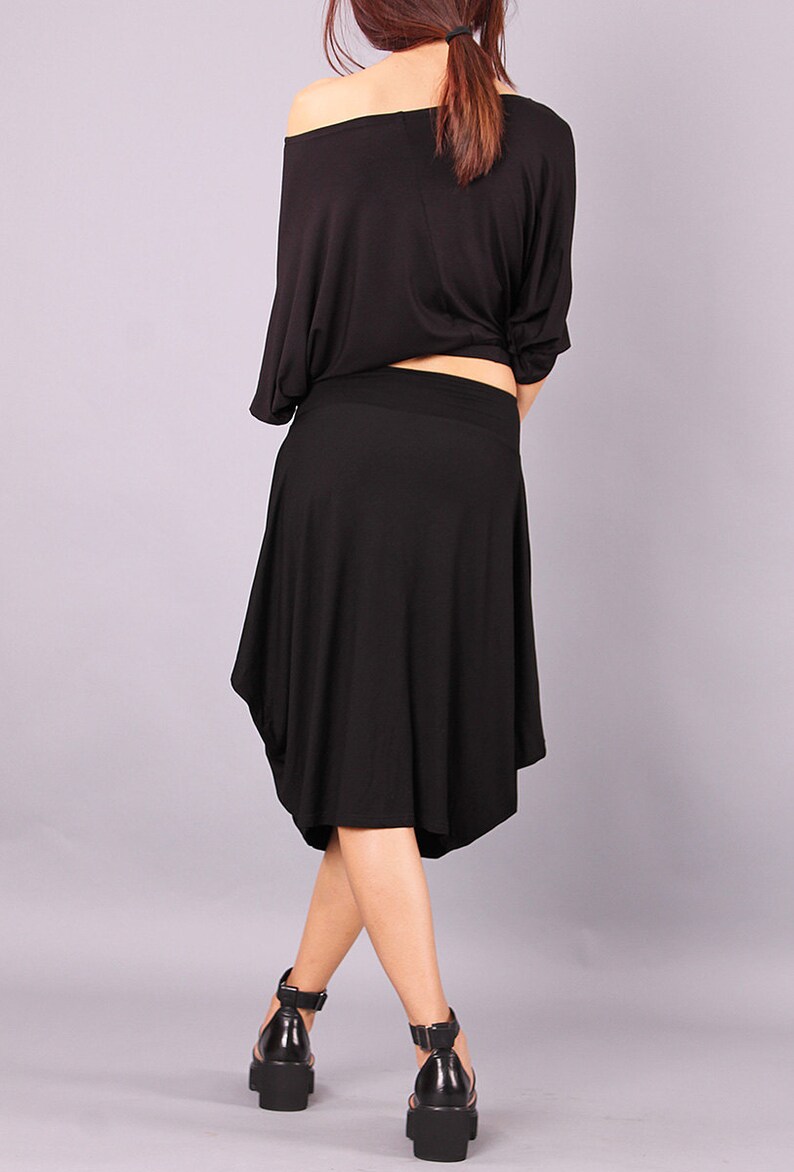May include: A black off-the-shoulder top with a loose fit and a black skirt with a flowing, asymmetrical hem.