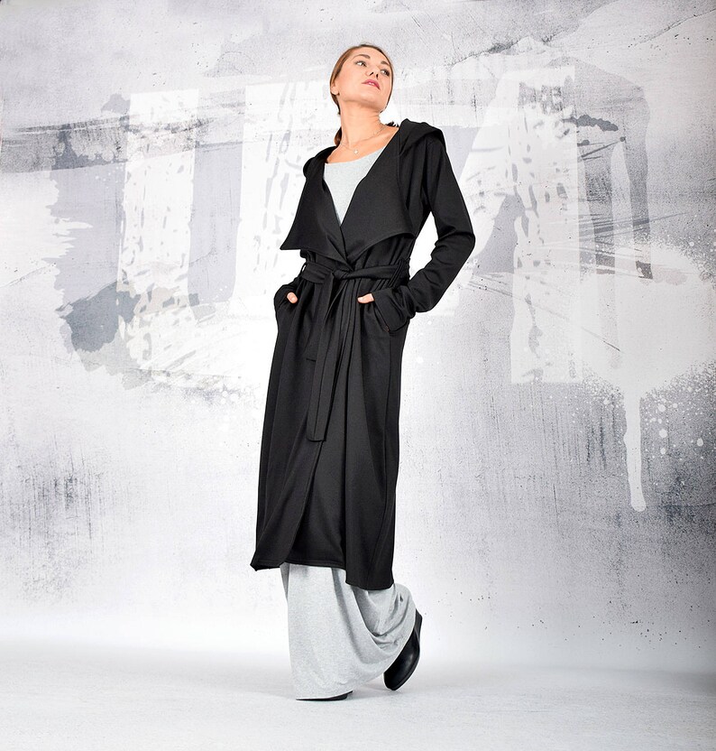 May include: A long black hooded cardigan with a tie belt. The cardigan is made of a soft, comfortable fabric and has a relaxed fit.