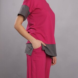 May include: A two-piece pajama set in pink and gray. The top has a short sleeve and a gray panel across the bottom. The pants have a relaxed fit.