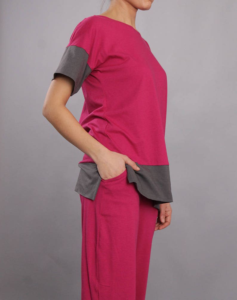 May include: A two-piece pajama set in pink and gray. The top has a short sleeve and a gray panel across the bottom. The pants have a relaxed fit.