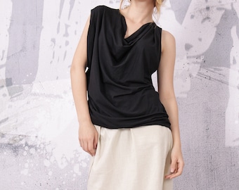Puede incluir: Una blusa negra sin mangas con cuello de pico y diseño drapeado. La blusa se combina con una falda beige.