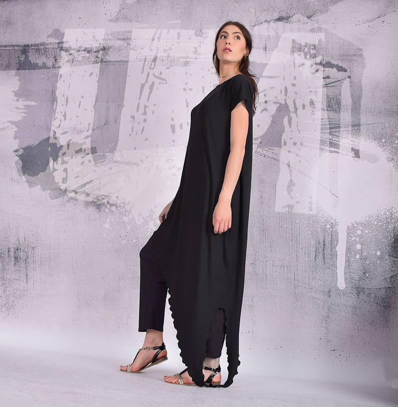 Puede incluir: Un vestido negro asim&eacute;trico de manga larga, con cuello redondo y falda amplia. El vestido est&aacute; hecho de una tela suave y c&oacute;moda y tiene un corte holgado.