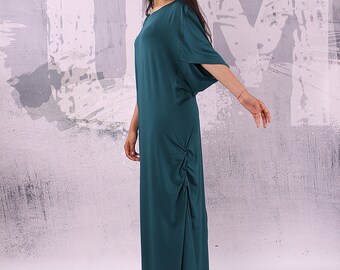 May include: A teal maxi dress with a gathered detail on the side. The dress has a relaxed fit and a round neckline.