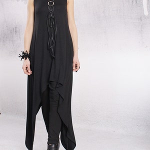 Könnte beinhalten: Ein schwarzes, ärmelloses Maxikleid mit einem hohen, niedrigen Saum. Das Kleid hat eine lange, schwarze Lederkette mit einem silbernen Ringakzent.