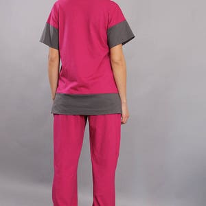 May include: A two-piece pajama set in pink and gray. The top has short sleeves and a gray band at the bottom. The pants are long and have a relaxed fit.
