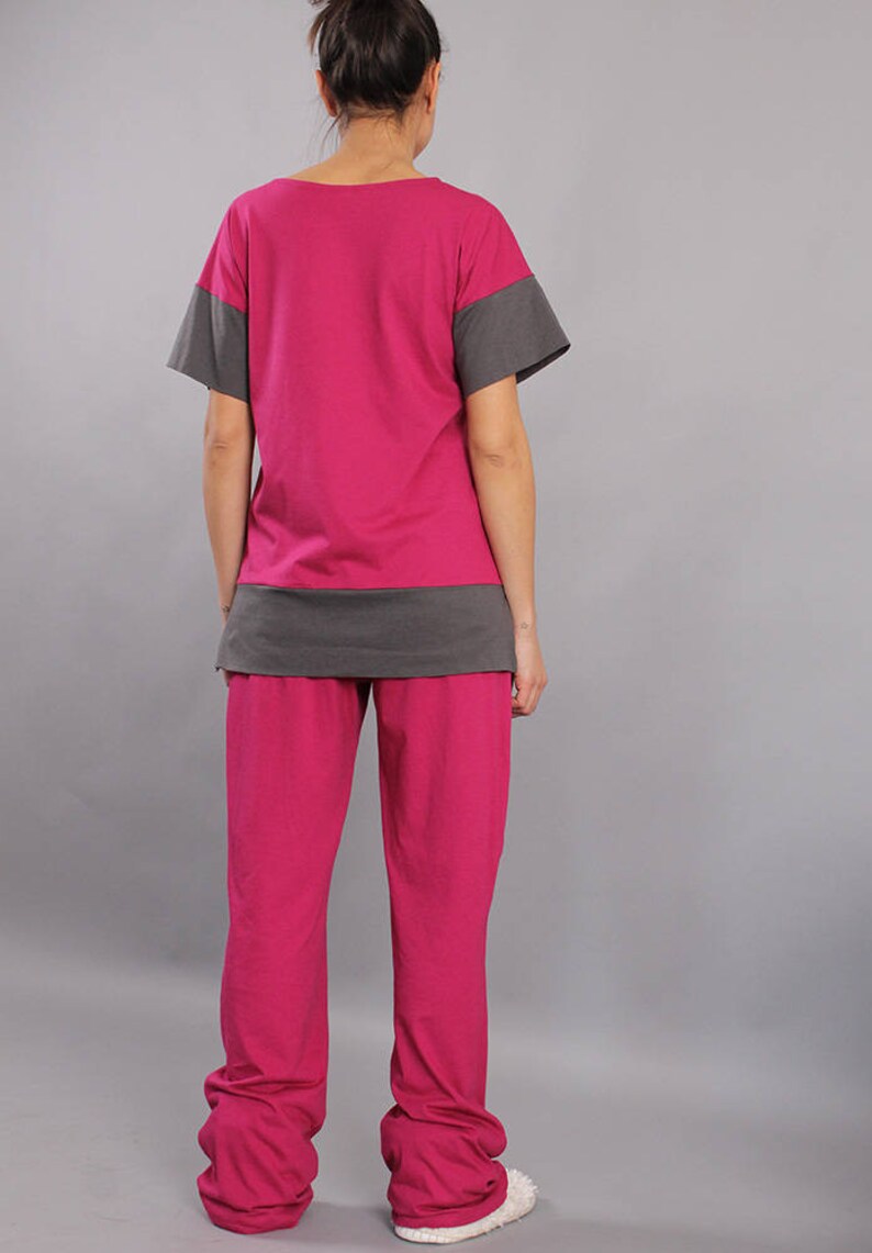 May include: A two-piece pajama set in pink and gray. The top has short sleeves and a gray band at the bottom. The pants are long and have a relaxed fit.