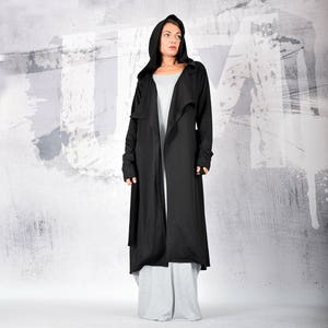 May include: A long black hooded cardigan with a draped front and long sleeves. The cardigan is made of a soft, lightweight fabric and has a relaxed fit.