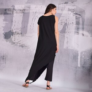 Puede incluir: Un vestido negro asim&eacute;trico maxi con una sola correa y un dobladillo alto-bajo. El vestido est&aacute; hecho de una tela suave y fluida y tiene un ajuste relajado.