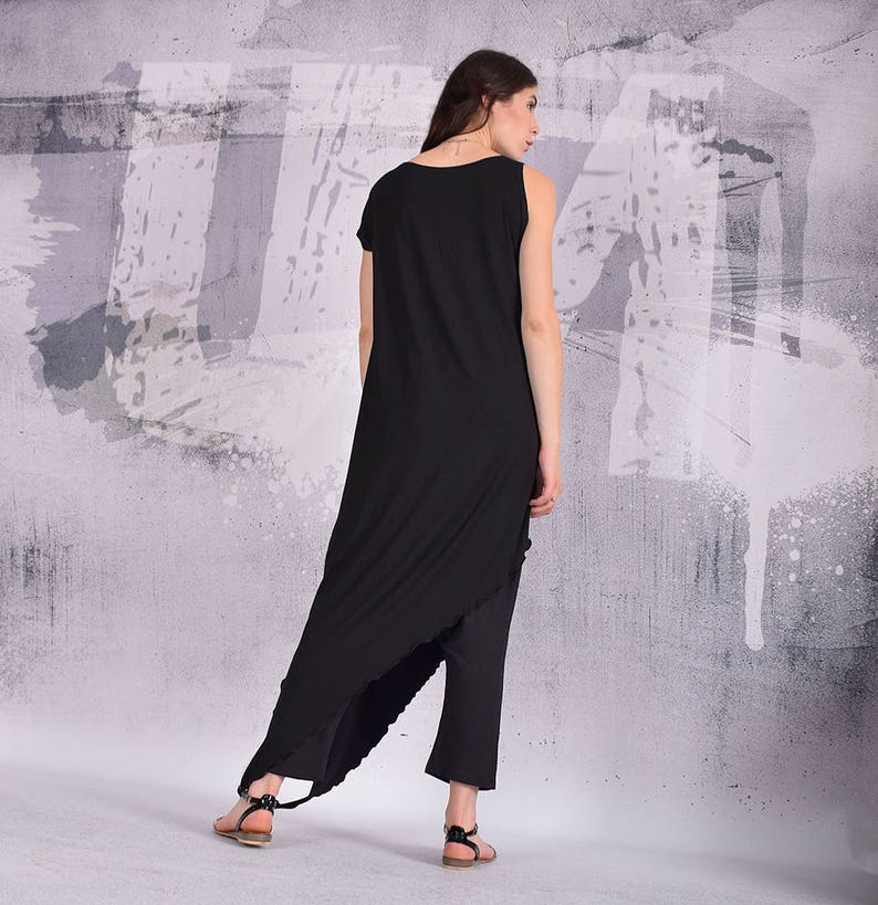 Puede incluir: Un vestido negro asim&eacute;trico maxi con una sola correa y un dobladillo alto-bajo. El vestido est&aacute; hecho de una tela suave y fluida y tiene un ajuste relajado.