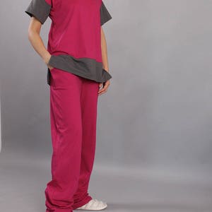 May include: A two-piece outfit in pink and gray. The top is a loose-fitting t-shirt with a gray band across the bottom. The pants are a relaxed fit with a straight leg.