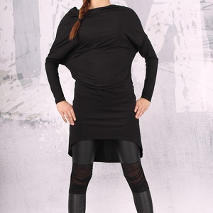 May include: A black long-sleeved tunic with a draped neckline and a high-low hemline. The tunic is paired with black leggings that have a mesh panel detail.