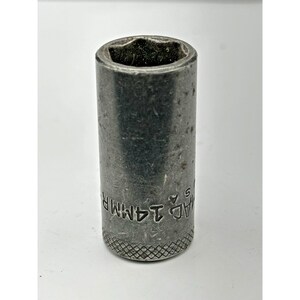 May include: A cylindrical silver-colored metal socket tool with a six-point interior opening. The exterior surface features a knurled base for grip and is stamped with the text 14MM and MAC USA. The metal shows signs of wear and surface scratches.