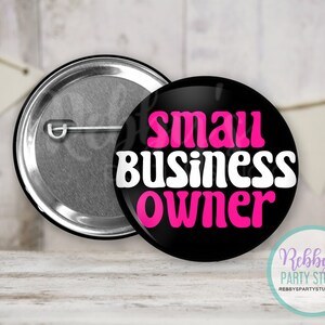 May include: Black button with white text that reads "small business owner" in a retro font. The text "owner" is in pink. The button has a silver back.
